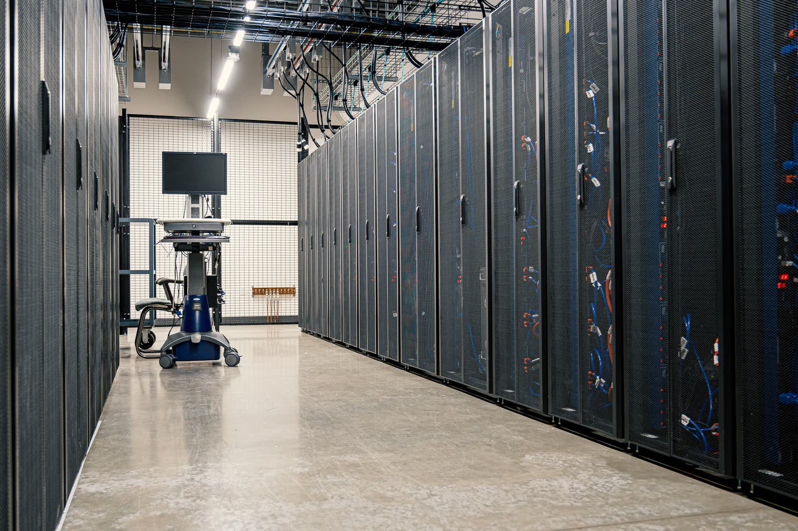 Data centre aisle with server racks and network cabling